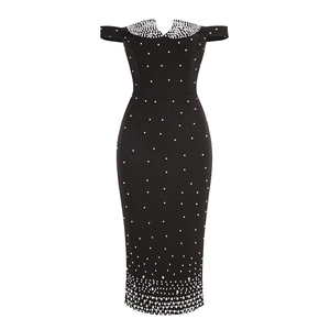 Détail de robe noire à épaules dénudées avec perles blanches et taille cintrée