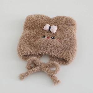 Close-up of plush brown cat hat featuring embroidered face and pink checkered bow detail