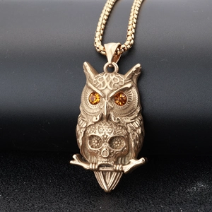 Vintage gold owl skull pendant necklace with orange gems and box chain on black background