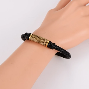Braided black leather bracelet featuring a textured gold metal cylinder and black spacer beads