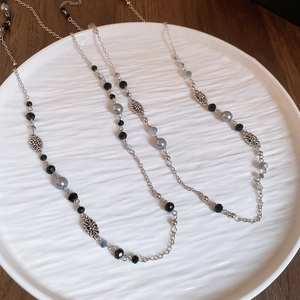 Detail of silver flower charm and pearl bead necklace on elegant white tray