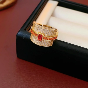 Macro shot of luxury gold ring with emerald-cut red stone and paved zircon details