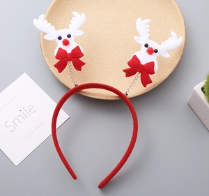 Detail of Christmas reindeer headband with white antlers and red bow on wooden tray