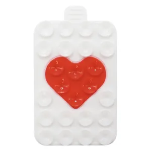 Detail of a rectangular silicone phone suction mat with a red heart design on white surface