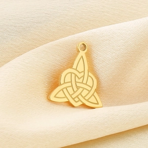 Vue détaillée d'un pendentif cœur à nœud celtique doré sur un tissu en soie beige