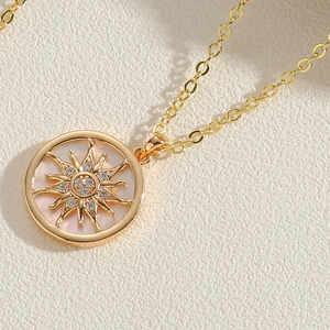 Détail du collier pendentif soleil doré avec incrustation de nacre et petits zircons