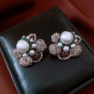Detailed view of vintage flower earrings featuring large pearls and green rhinestones