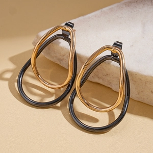 Detail of teardrop geometric stud earrings with layered black and gold oval metal rings