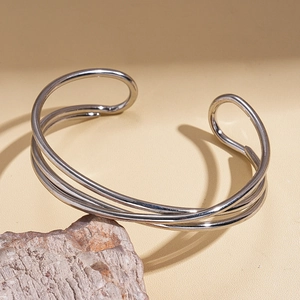 Detail view of multilayer geometric silver bangle set on a decorative rock pedestal