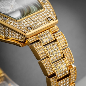 Macro shot of gold tonneau-shaped watch featuring full diamond-encrusted case and bracelet