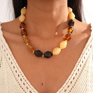 Close-up of vintage acrylic oval beaded necklace with amber and beige stones on a model