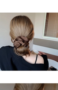 Close-up of a glossy brown satin hair scrunchie with elegant pleated silk texture