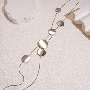 Detailed macro view of silver long tassel necklace with polished circular metal discs
