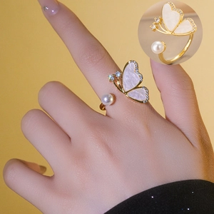Bague ouverte papillon dorée avec nacre blanche et perle élégante portée au doigt