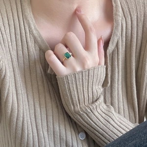 Close-up of 925 silver gold-plated ring with rectangular green emerald on hand