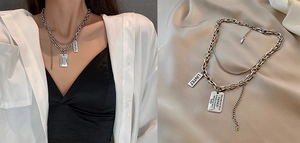 Macro detail of silver double-layered titanium steel necklace with engraved rectangular pendant
