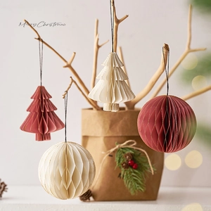 Decorazioni natalizie in origami e palle a nido d'ape appese ai rami con toni caldi