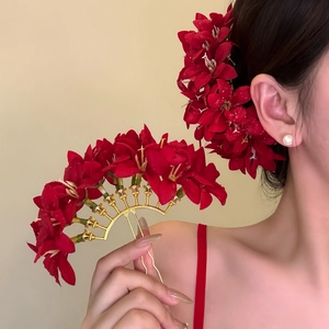 Close-up of red fabric flower hair fork with golden vintage fan-shaped metal pins