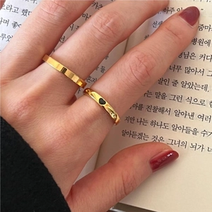 Detail of minimalist gold-plated ring set with black heart motif on vintage book background