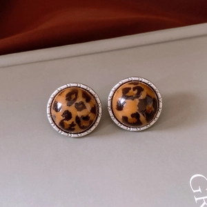 Gros plan de boucles d'oreilles rondes en acrylique léopard avec bordure perlée argentée
