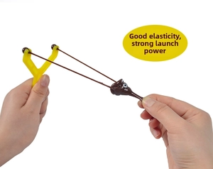 Close-up of stretchy brown poop toy being launched with a yellow finger slingshot
