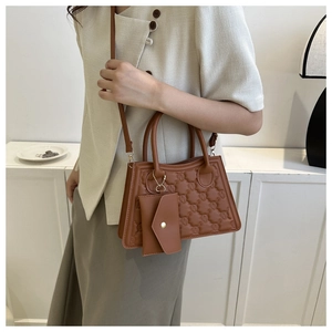 Brown quilted square handbag with matching charm shown on a casual chic model