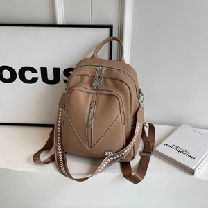 Detailed view of khaki pebbled leather backpack with multiple zippers and woven strap