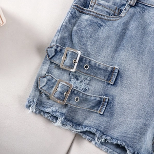 Close-up of light blue denim shorts featuring metal ring details and frayed raw edges