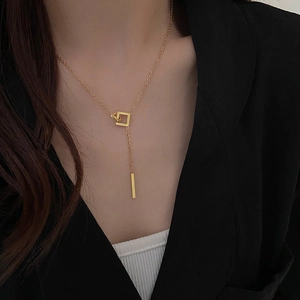Detail of 18k gold plated Y-shaped necklace with geometric square buckle on black outfit
