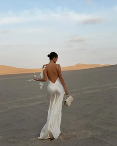 Back view of a sexy white satin backless dress with a cowl neck in a desert setting