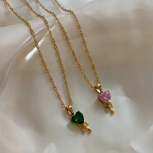 Golden heart zircon necklace set with melting metal design on white silk background