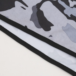Detail of grey camouflage balaclava showing fine mesh fabric and black stitched edging