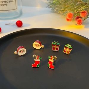 Detail view of festive Christmas earrings set featuring Santa and gift boxes on tray
