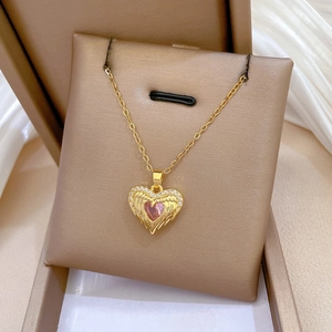 Detail of pink heart gemstone necklace with pavé wings on champagne velvet padding