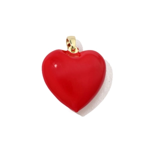Macro view of a vibrant red heart-shaped pendant with a polished gold bail on white backdrop
