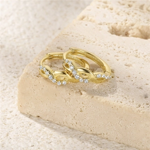 Macro view of gold S925 silver wave-style earrings with sparkling paved zircons