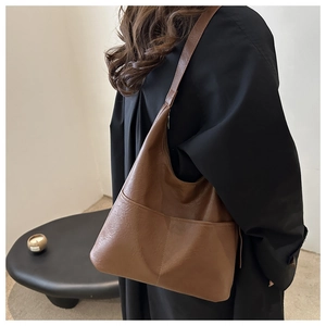 Side view of dark brown faux leather tote bag worn by a model in a minimalist setting