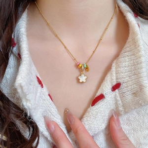 Close-up of golden necklace with white shell star pendant and colorful ring charms
