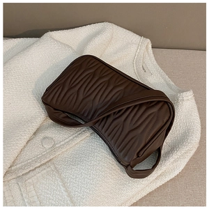 Detail of dark brown shoulder bag with embossed ripple texture on white tweed fabric