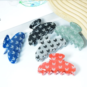 Five assorted glitter butterfly hair claws in PVC material on a decorative wooden tray