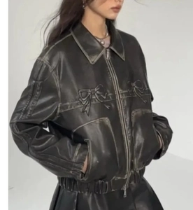 Détail d'une veste vintage en cuir marron avec broderie de nœuds symétriques sur la poitrine