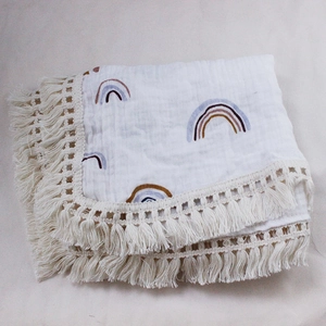 Detail of soft cotton baby blanket featuring rainbow print and delicate tassel edges