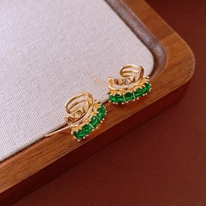Gros plan sur des boucles d'oreilles vintage dorées avec pierres vert émeraude