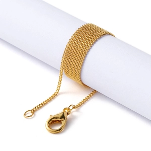 Detail of gold-plated thin chain necklace wrapped on white prop with lobster clasp