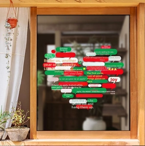Close-up of colorful Christmas window clings with festive speech bubbles on a wooden window