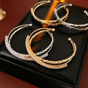 Detailed view of layered crossover bangles with colorful zircons on a leather jewelry box