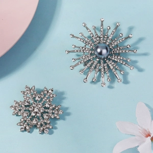Detailed view of silver snowflake brooch and starburst pin with sparkling rhinestones