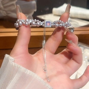 Gros plan sur un bracelet à double rang de perles mauves avec pendentif en zircon et glands