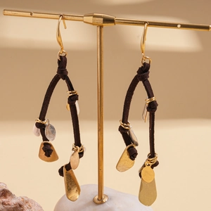 Detail of bohemian drop earrings with brown tassels and metallic sequins on a gold stand