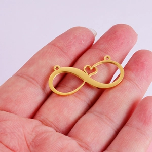 Golden heart infinity symbol pendant in stainless steel held in palm for scale